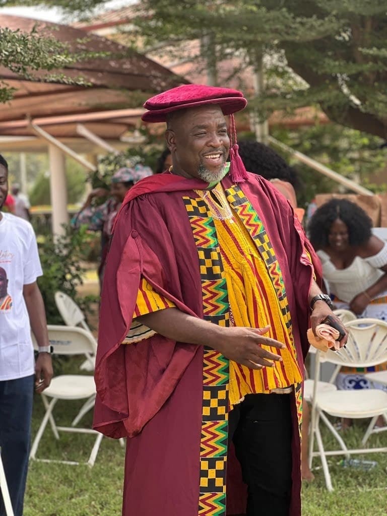 Nathaniel Adams, smiling, in a red, yellow and green striped smock